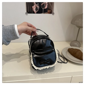 Detailansicht eines schwarzen Mini-Rucksacks mit weißer Spitze und Schleifenakzent