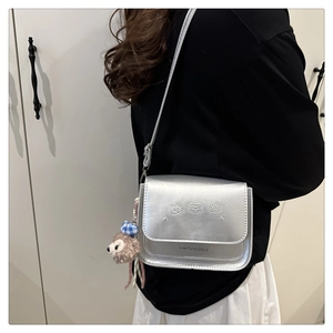 Détail d'un sac bandoulière argenté métallisé avec gaufrage dessin animé et ours en peluche