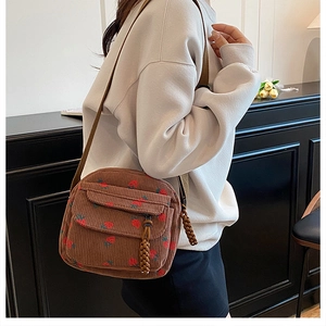 Detailed shot of brown corduroy crossbody bag with strawberry print on a model