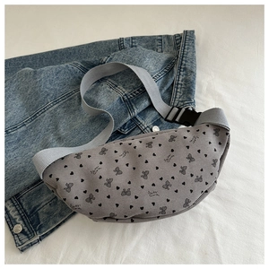 Detalle del bolso de pecho de pana con estampados de corazones negros y lazos grises y hebilla