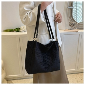 Detail of black quilted large tote bag featuring gold ring hardware and soft texture