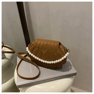 Detail of brown shell-shaped handbag with snake texture and elegant pearl handle