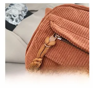Detailed close-up of corduroy texture and smooth metal zipper on a brown handbag