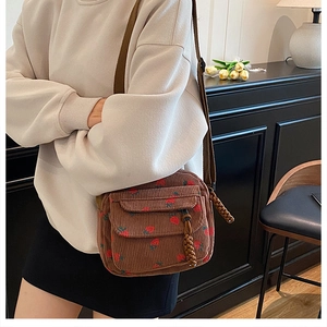 Detail of brown corduroy crossbody bag with strawberry print and textured fabric