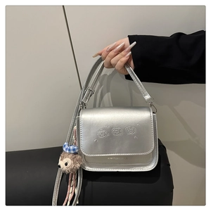 Détail du sac argenté métallisé avec gaufrage d'animaux et breloque en peluche