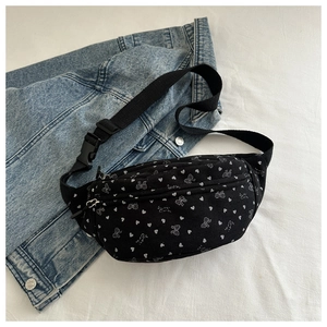 Detalle de riñonera de pana negra con estampado de corazones sobre chaqueta vaquera