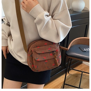Detail view of brown corduroy crossbody bag featuring a cute red strawberry print pattern