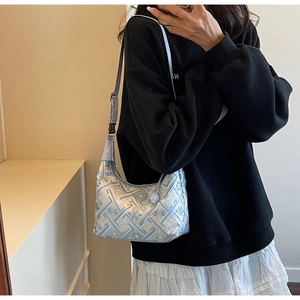 Close-up of light blue floral embroidery and silver buckle on adjustable shoulder bag