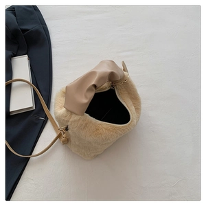 Détail du sac bandoulière en peluche avec zip doré et texture fausse fourrure sur tissu blanc