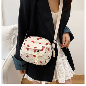 Detail of white corduroy crossbody bag with strawberry print and adjustable strap