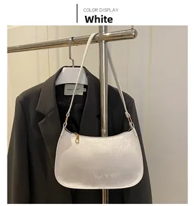 Detail view of the white snakeskin embossed texture and golden zipper on the underarm bag