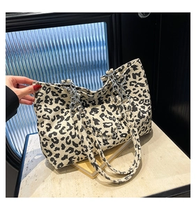 Detail of leopard print corduroy tote bag featuring a silver chain and pearl accent