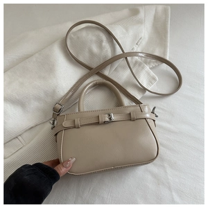Détail d'un sac à main beige en simili cuir avec boucle argentée sur tissu côtelé
