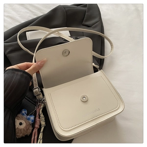 Détail du sac en cuir blanc cassé avec logo de marque, fermoir magnétique et bijou de sac