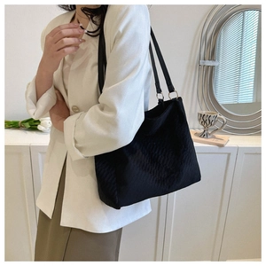 Close-up of black quilted large tote bag with elegant chain strap and diamond pattern detail