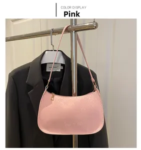 Detail of pink faux snakeskin underarm bag with gold zipper hanging on a hanger