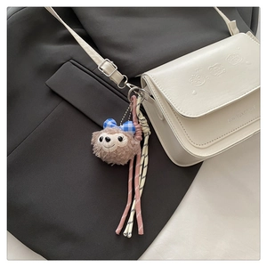 Détail d'un petit sac carré blanc cassé avec ours embossés et pendentif ours en peluche