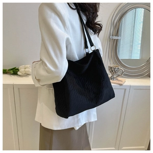 Detail of black corduroy tote bag showing textured fabric and leather shoulder strap