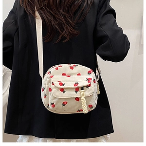 Detailed texture of beige corduroy crossbody bag with cute red strawberry print pattern