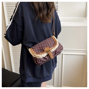 Close-up of polka dot pattern and white lace edge detail on a brown crossbody bag