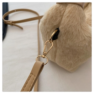 Détail d'un sac à main beige en peluche avec boucle dorée et bandoulière en cuir