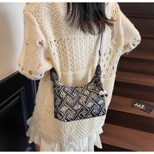 Detailed view of black and white geometric pattern dumpling bag worn by model on stairs
