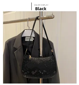 Close-up of black faux snakeskin leather baguette bag with shiny texture and golden zipper