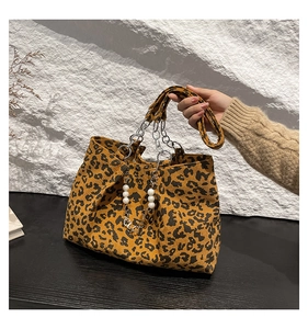 Detail of leopard print corduroy tote bag featuring a chic metal chain and white pearls