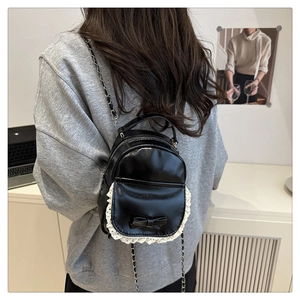 Schwarzer Mini-Rucksack aus PU-Leder mit weißer Spitze und Schleife an einem Model gezeigt