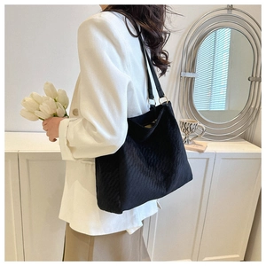 Quilted black tote bag showing large capacity and elegant matte texture on shoulder