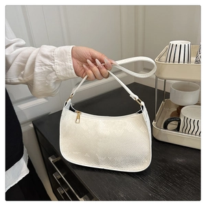 Detail of white faux snakeskin crescent bag with premium gold zipper and textured finish