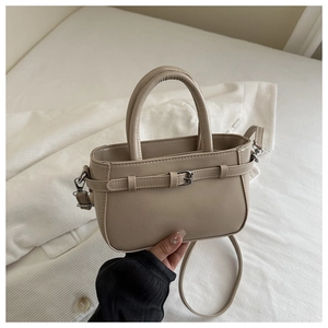 Gros plan sur un sac à main en cuir beige grainé avec boucle décorative et poignée