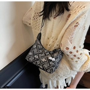Close-up of ethnic style embroidery and decorative beads on a black shoulder bag