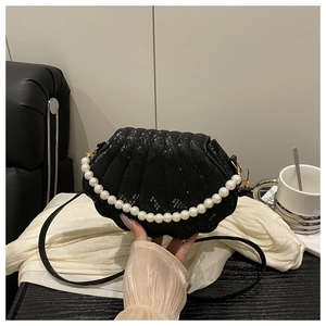 Close-up of black shell-shaped handbag with snake pattern texture and pearl handle