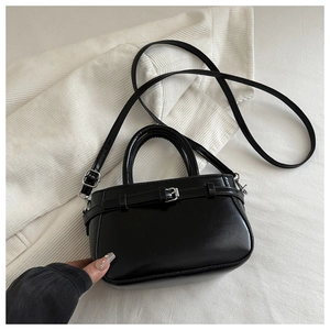 Détail d'un sac à main en cuir noir avec texture brillante et boucle argentée