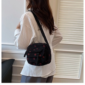 Detailed back view of a corduroy crossbody bag with strawberry print and black woven strap
