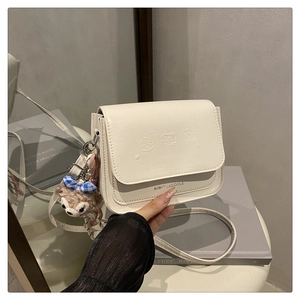 Détail du sac en cuir crème avec ours en relief et accessoire de charme en peluche