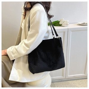 Detail of black large capacity tote bag with geometric texture and golden hardware