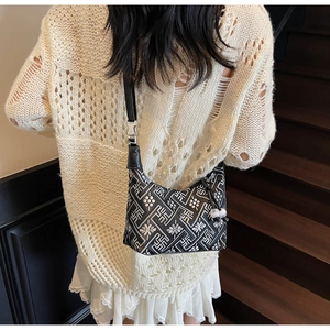 Détail du sac à bandoulière aux motifs géométriques noir et blanc avec pompon porté