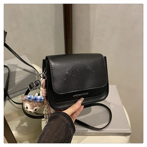 Détail du sac à rabat en PU noir avec ours embossés et pendentif en peluche