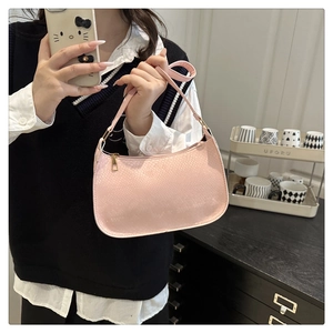 Detail of pink crocodile texture shoulder bag with golden zipper and slim strap