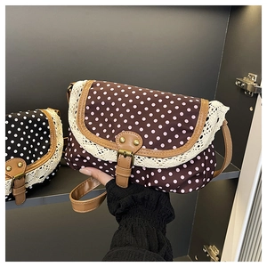 Close-up of retro polka dot canvas bag featuring lace edges and brown leather buckle strap