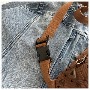Detalle de correa ajustable y hebilla en bolso bandolera con estampado floral y corazones