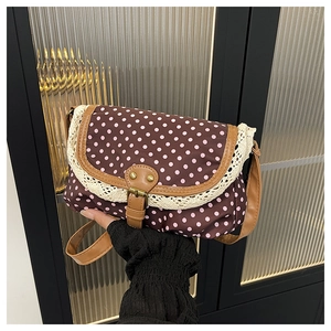 Detail of retro polka dot canvas bag with white lace trim and leather buckle