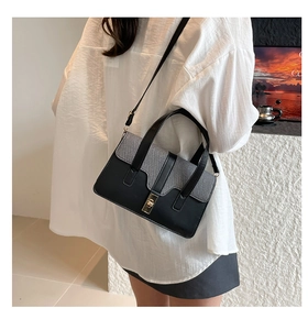 Détail du sac contrasté noir et gris avec fermoir rotatif doré et rabat en tissu texturé