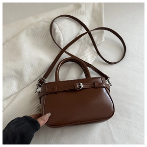 Détail d'un sac Boston marron foncé avec boucle argentée et texture en cuir grainé
