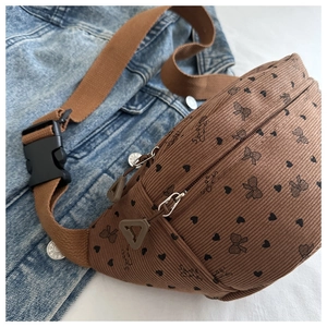 Detalle de riñonera de pana marrón con estampado de corazones y lazos sobre denim