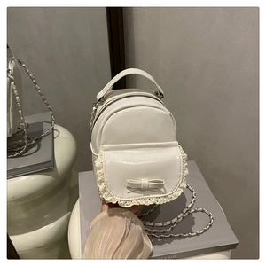 Detailansicht eines weißen Mini-Rucksacks mit Spitzenbesatz und eleganter Schleife