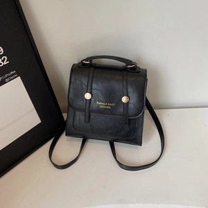 Retro black PU leather backpack with gold hardware and top handle in minimalist setting