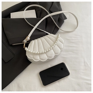 Close-up of white shell-shaped bag with snakeskin texture and pearl strap detail